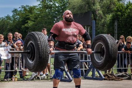 Almaty, Kazakhstan - May 28, 2017. strong man raises a heavy barbell. Weightlifting. City fesitwal sport on the street for a healthy lifestyle. Sports contests for arm-wrestling, heavy lifting, tug-of-war, army bench pressのeditorial素材
