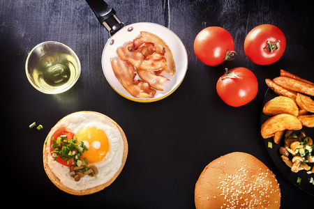 Fried egg on bread. English breakfast with bacon, fried potatoes, mushrooms and greens. Black background.の写真素材