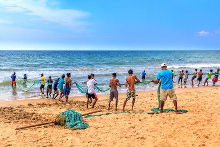 Colombo, Sri Lanka - January 14, 2018. Fishermen pull a trawl with a catch on the beach on a sunny dayのeditorial素材