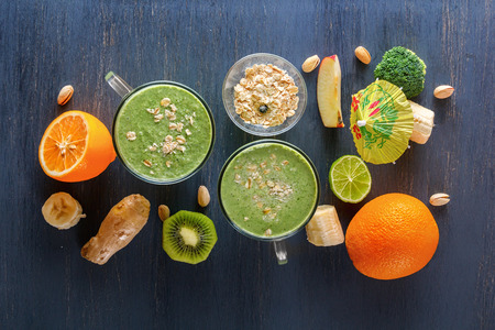 Fresh green smoothies in a glass with vegetables, fruits and oat chlorine on a wooden table. Top view. The concept of a healthy diet.の写真素材