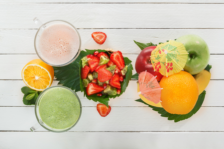 Fresh green smoothies and a milkshake of strawberries in glass glasses with tropical fruits on white boards. View top. The concept of a healthy diet.の写真素材