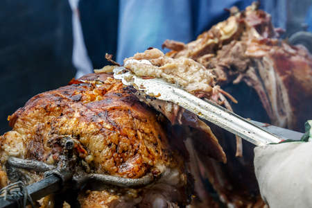 Chef cuts the finished lamb into pieces on a spit over hot coals. Outdoor grillの写真素材