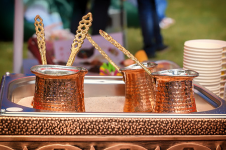 Bright brass cezves stand on the street in a box with hot sandの写真素材