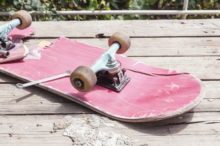 The old broken skateboard lies with a spanner on a wooden table in the open air. Tonedの写真素材