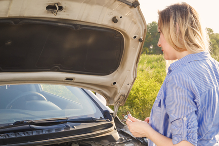A girl is repairing a car on a country road.の写真素材