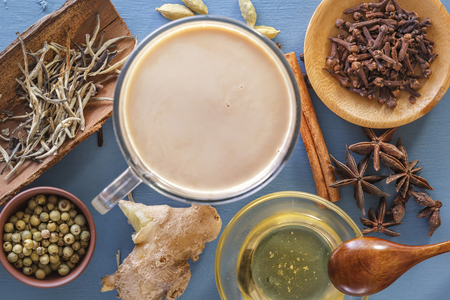 Hot Indian milk tea with spices - cinnamon, cardamom, ginger, cloves, tubby, sweet pepper on a wine background. View from above. Close-upの写真素材
