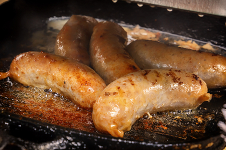 Sausages are fried in boiling oil in a hot frying pan. Close-upの写真素材