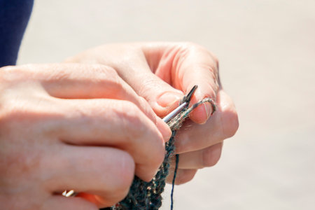 woman knits on knitting needles out of wool on the street on a sunny day. Close-up. Copy space.