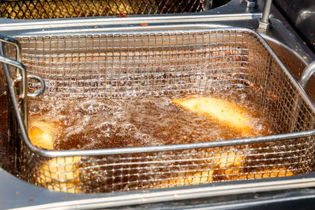 Pies are fried on hot oil in a stainless steel fryer in a street fast food cafeの写真素材