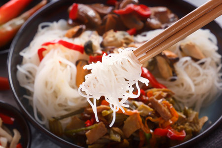 Traditional Chinese wooden chopsticks with coiled rice noodles. Close-up