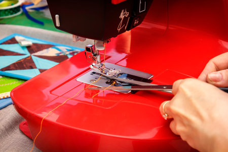 Seamstress with scissors cuts the thread on the sewing machine. Close-up