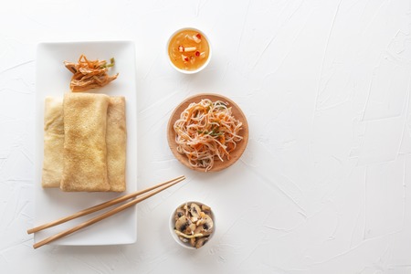 Traditional snacks of Chinese cuisine Dim Sum - tortillas - bings in a plate on a white background, spicy salads, vegetables, noodles. View from above.の写真素材