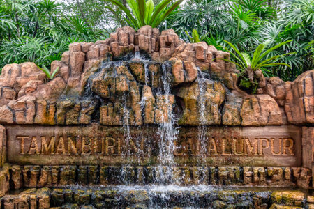 Kuala Lumpur, Malaysia - January 1, 2019. Stylized signboard at the entrance to the park of birds of granite stones with a small artificial waterfallのeditorial素材