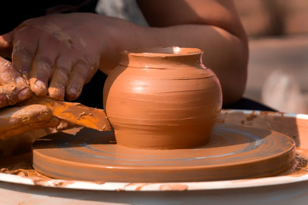 Hands of a street potter make a clay pot on a potter's wheel. Close-up