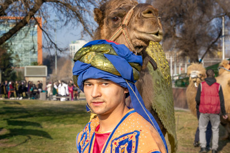Almaty, Kazakhstan - March 21, 2019. Camel driver wearing traditional national clothes leads a camel...
