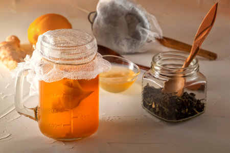 Homemade fermented drink Kombucha in glass jar with lemon and honey on a wooden table. Close-up