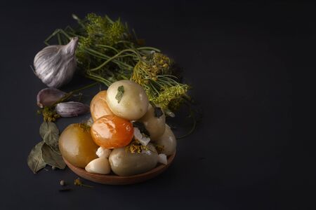 Salted tomatoes in a wooden plate on a dark table along with spices for salting. Copy space. Low key.の写真素材