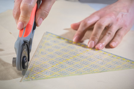 Tailor's knife in a woman's hand cuts the fabric. close-up.の写真素材