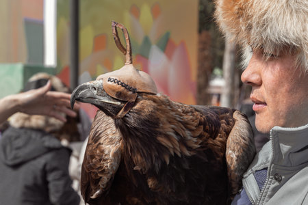 Almaty, Kazakhstan - March 21, 2022. Berkutchi is a hunter with a bird. A guy in national clothes holds a falcon on his hand. portrait. close-upのeditorial素材