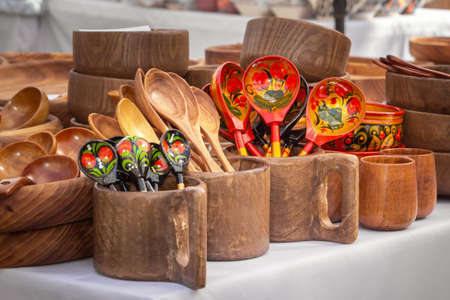 Wooden spoons and mugs with artistic painting on the counter of a street stall. Handmadeの写真素材