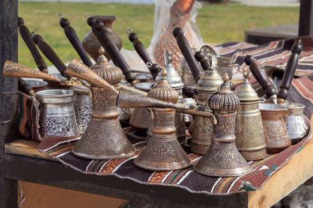 Traditional metal cezves with engraved ornaments are sold in a street shop. Handmadeの写真素材