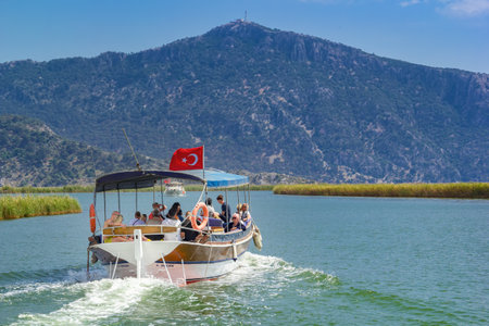 Dalyan, Turkey - May 9, 2022. Tourist pleasure boats transport tourists along the river against the backdrop of forested mountains and a cloudy skyのeditorial素材