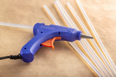 Electric blue hot glue gun with glue sticks on kraft paper backgroundの写真素材