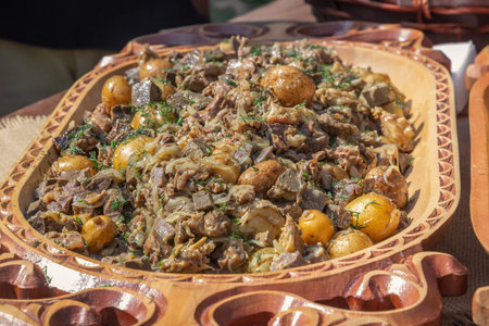 Traditional Asian dish kaurdak of fried meat, liver, kidneys, liver, potatoes, onions on a wooden platter. close-upの写真素材