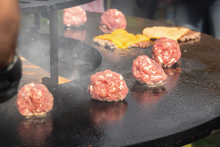 Meatballs are cooked in smoke on the frying plate of the grill of a street fast food restaurant.の写真素材