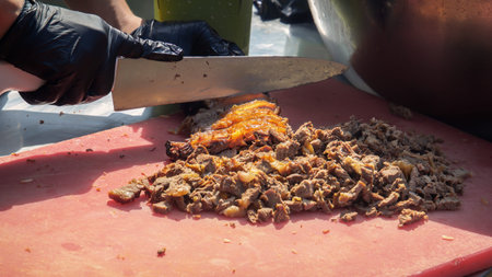 Cook cuts fried meat with a kitchen knife for the dishes of a street fast food restaurant.の写真素材