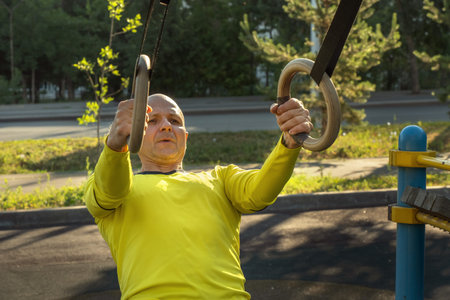 man trains with gymnastic rings on a street sports ground on a sunny day. healthy lifestyle....
