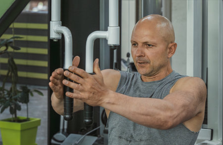 Muscular man flexing his arms in a pectoral muscle machine in the gym. close-upの写真素材
