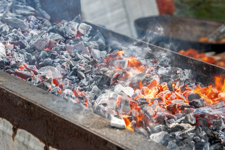 Fire and smoldering coals inside a metal grill for frying meat or vegetables outdoors. Preparing for...