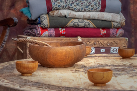 Traditional Asian wooden utensils for milk drinks stand on a low table against the background of a chest with blankets inside a nomadic home - a yurt. Close-upの写真素材