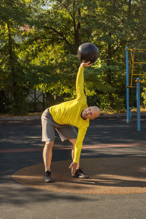 Man performs an exercise with a medicine ball on a street sports ground. Healthy lifestyleの写真素材