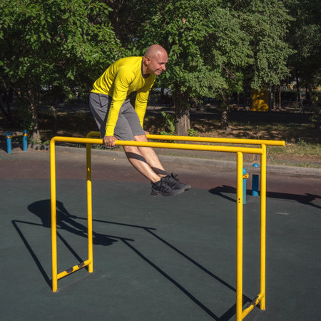 Man performs an exercise on parallel bars on a street sports ground on a summer sunny day. healthy lifestyleの写真素材