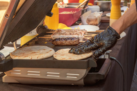 Cooking bread cakes and meat kebabs on an electric grill in a street cafe. Close-upの写真素材
