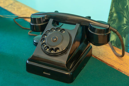 Old rotary telephone stands on a desk with a green cloth