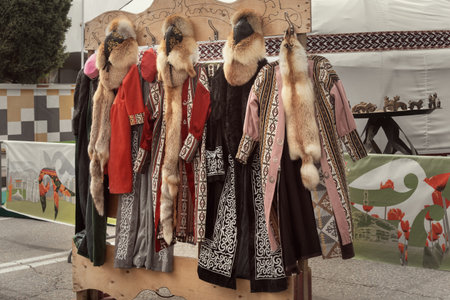 Traditional Kazakh robes and leather hats with natural fur are sold in a street store against the...
