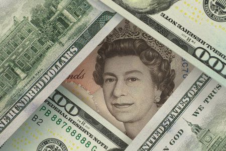 Portrait of the Queen of Great Britain on a pound sterling bill peeks out from under dollar bills. Foreign exchange market. Finance conceptの写真素材