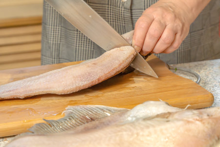 Chef cuts fresh fish into pieces with a knife