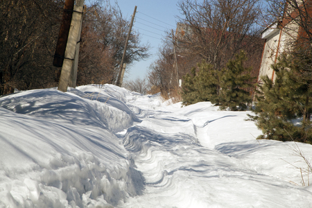 Snow-covered road in the village. White passageの写真素材