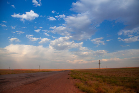 Highway. Blue with orange gradient sky with big clouds. Clouds cover the sun and droping sunrays down the earthの写真素材