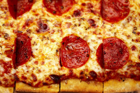 Hot big pepperoni pizza tasty pizza composition with melting cheese bacon tomatoes ham paprika steam smoke on black backgroundの写真素材