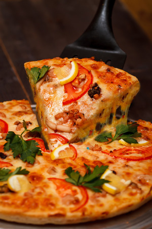 Hot big pepperoni pizza tasty pizza composition with melting cheese bacon tomatoes ham paprika steam smoke on black backgroundの写真素材