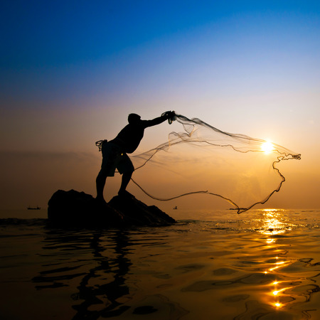 Fisherman with net at sunsetの写真素材