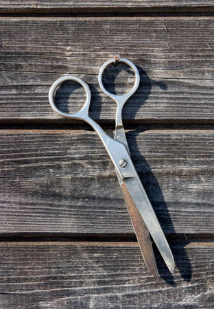 shabby metal rusty scissors hanging on wooden board wall closeup