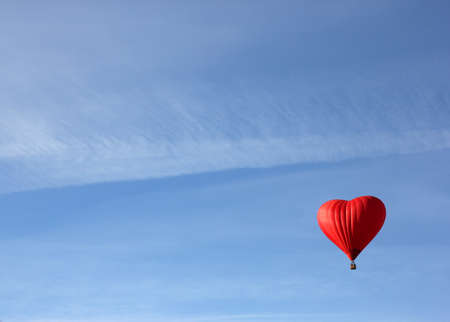 red balloon in the shape of red heart on a morning clear blue sky as a backgroundの写真素材
