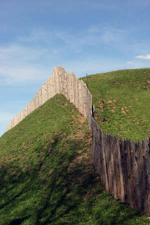 the wooden palisade on the green grass shaft of the ancient fortress and city and blue sky as a background, Torzhok, Russiaの写真素材