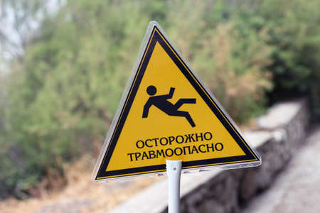 triangular yellow sign with inscription caution traumatic and image of falling man closeupの写真素材